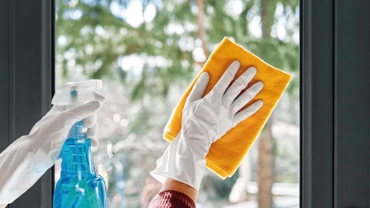 Applying window glass cleaner spray and wiping with microfiber cloth
