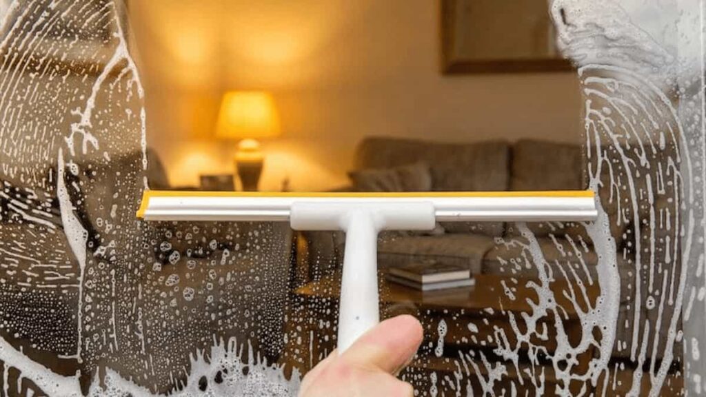Cleaning window glass with squeegee and soap solution for streak-free finish
